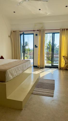 a large bedroom with a large bed and a balcony at Calma Cafe - Surf, Stay and Yoga in Dickwella