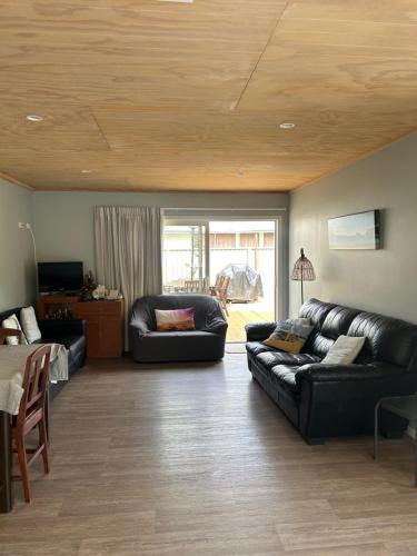 ein Wohnzimmer mit einer schwarzen Ledercouch und einem Tisch in der Unterkunft Graydon Grove in Kaiteriteri