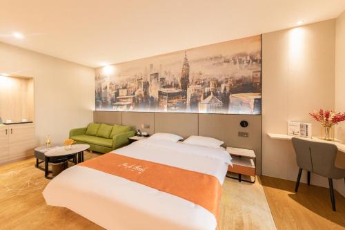 a bedroom with a large bed and a green couch at Youth Innovation Apartment in Guangzhou
