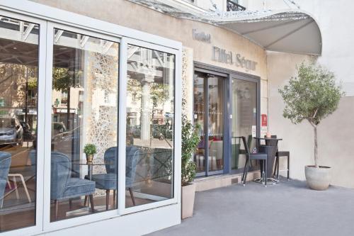 a store front with glass doors and chairs and tables at Hotel Eiffel Segur in Paris