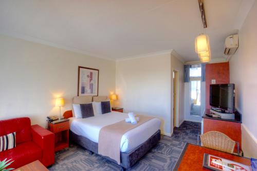 a hotel room with a bed and a red couch at The Sandridge Motel in Lorne