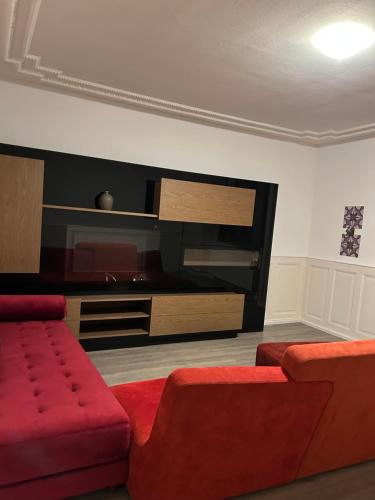 een woonkamer met een rode bank en een flatscreen-tv bij Le séjour in Tramelan