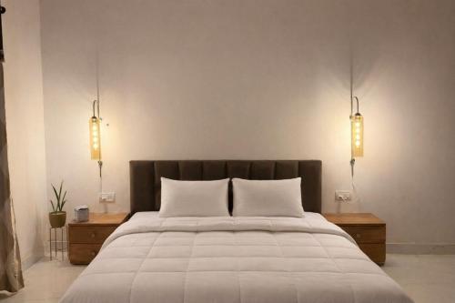 a bedroom with a large white bed with two lights at The RB's Farm in Fīrozābād