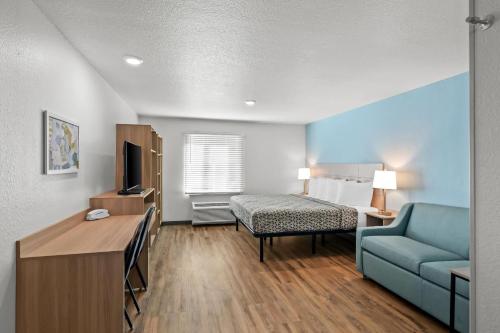 a hotel room with a bed and a blue couch at WoodSpring Suites Palm Springs - West Palm Beach in Palm Springs