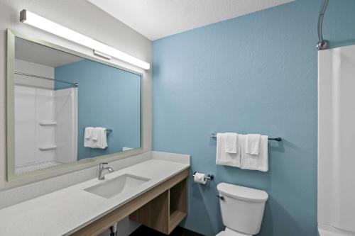 a bathroom with a sink and a mirror and a toilet at WoodSpring Suites Palm Springs - West Palm Beach in Palm Springs