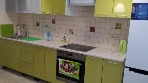 cocina con armarios de color verde lima y fogones en Apartment Sofia 1, en Volgograd