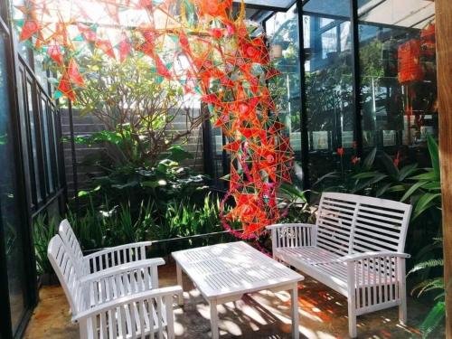 two white chairs and a table in a greenhouse at Jrai Homestay in Pleiku