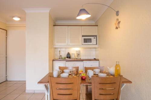 a kitchen with a table and two chairs and a kitchen with at Résidence Pierre & Vacances Bleu Marine in Lacanau-Océan