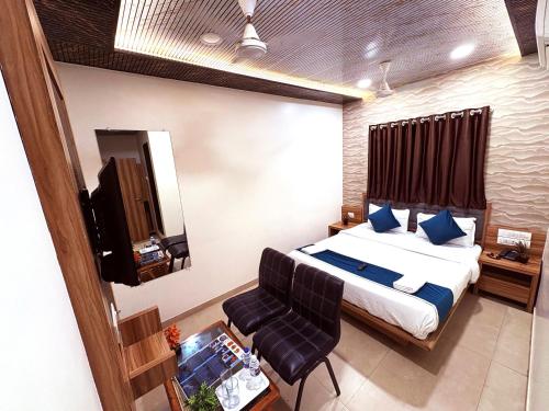 a bedroom with a bed and a chair and a television at Sai Sagar Lodging & Boarding in Ulhasnagar