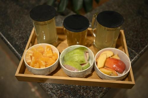 een dienblad met drie kommen eten en twee glazen bij VSR Vriksha Wellness Nature Cure Center in Hyderabad