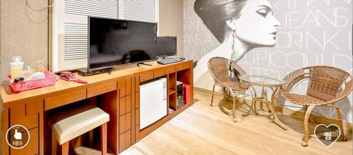 a room with a desk with a television and two chairs at Happy Q Motel in Andong