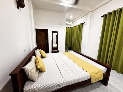 een bed in een kamer met groene gordijnen bij Hagiazo Guest Inn Mirissa in Mirissa
