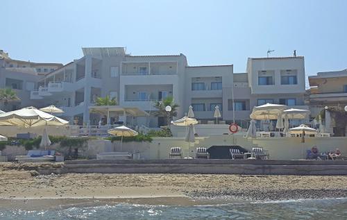 a large building with tables and umbrellas on the beach at Filoxenia Beach Hotel in Rethymno Town