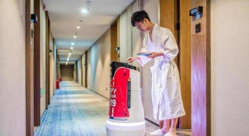 a man standing next to a appliance in a hallway at AURAYA BY SUNING NANJING XUZHUANG in Nanjing