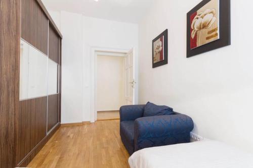 a room with a bed and a blue chair at City Break Apartments Chic and Luxury in Belgrade