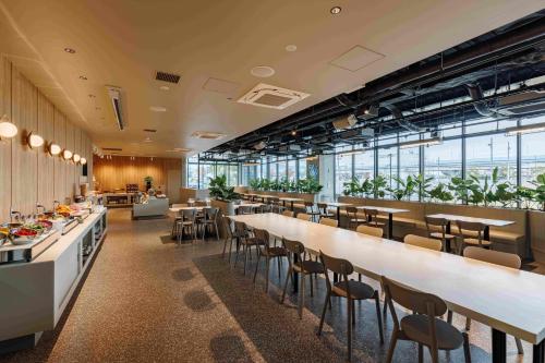 a restaurant with long tables and chairs and windows at Setouchi Cycle Stays Hiroshima Ujina in Hiroshima