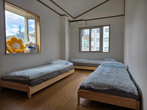 due letti in una stanza con due finestre di Kobe Youth Hostel a Kobe