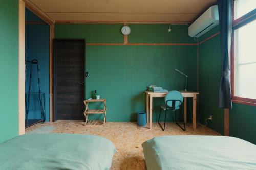 a bedroom with green walls and a desk and a bed at ペコレラ学舎 Teacher House in Yakumo