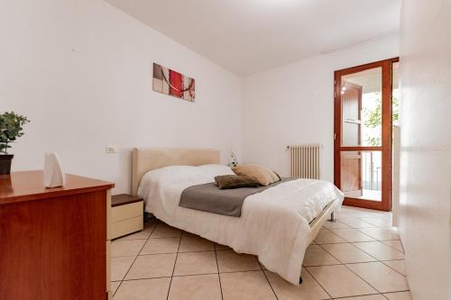 een witte slaapkamer met een bed en een raam bij Trilocale con giardino a Cervia - CV012 in Cervia