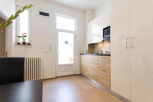 a kitchen with white walls and wooden cabinets and a window at City Break Apartments Chic and Luxury in Belgrade