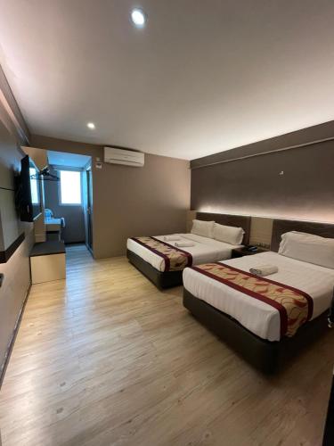 a hotel room with two beds and a flat screen tv at Palace Inn in Miri