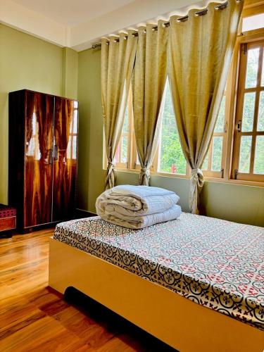 ein Schlafzimmer mit einem Bett in einem Zimmer mit Fenstern in der Unterkunft Pines Heaven Homestay in Kalimpong