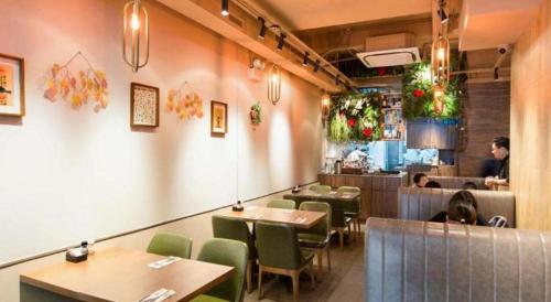 uma sala de jantar com mesas e cadeiras e uma pessoa num restaurante em Metroplace Olympic em Hong Kong