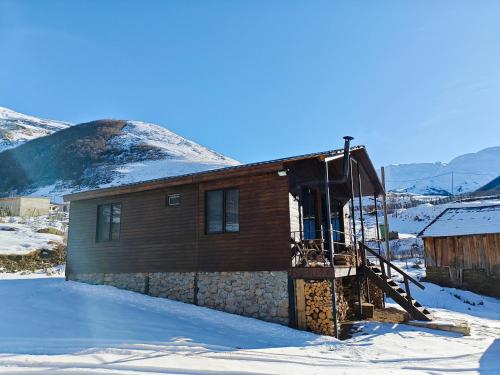 een houten huisje in de sneeuw met een trap bij Ushguli Highland Cottage in Ushguli