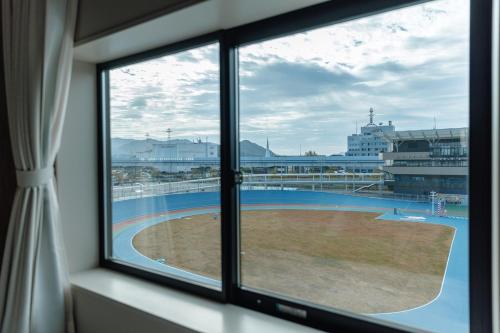 a window with a view of a soccer field at Setouchi Cycle Stays Hiroshima Ujina in Hiroshima
