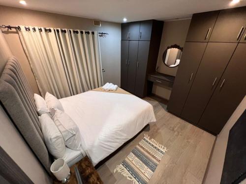 una camera da letto con un letto bianco e uno specchio di EastClaire Guesthouse a Krugersdorp