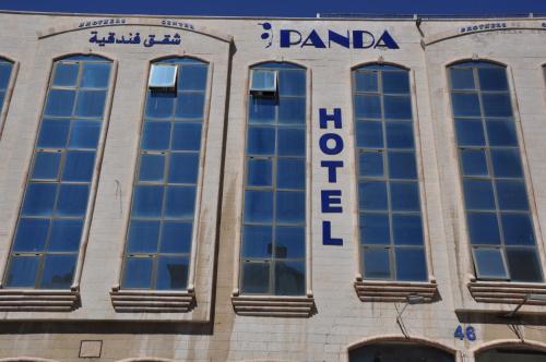 een bord aan de zijkant van een gebouw met ramen bij Panda Hotel Apartments in Amman