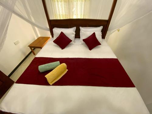 a bed with red and white sheets and pillows at Green Calm Villa in Kamburugamuwa