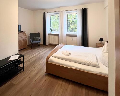 a bedroom with a bed and a chair and a window at Pension Lutter in Bodenwöhr