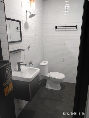 a white bathroom with a toilet and a sink at Moksu Garden Tiny House jerteh in Jertih