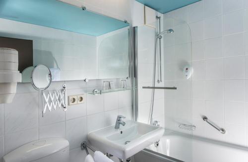 bagno con lavandino, servizi igienici e specchio di City Hotel Berlin East a Berlino