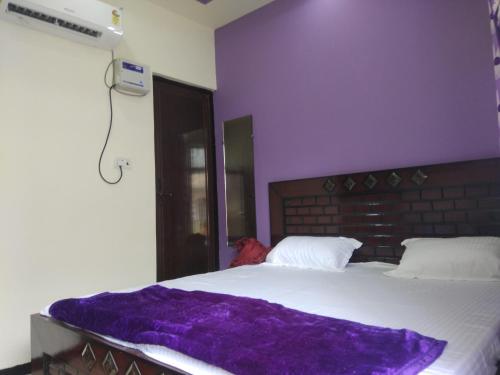 een slaapkamer met een bed met een paarse deken erop bij Sant-I Hotel in Kānpur