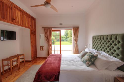 ein Schlafzimmer mit einem großen Bett mit grünem Kopfteil in der Unterkunft Wingrock Guesthouse in George