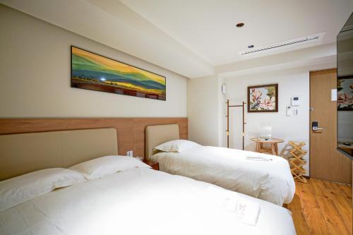 ein Schlafzimmer mit zwei Betten und einem Gemälde an der Wand in der Unterkunft 中野ワールドホテル in Tokio