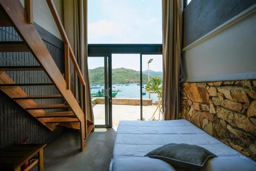 a bedroom with a bed and a stone wall at Rock Bay by Chành Rành in Vĩnh Hy