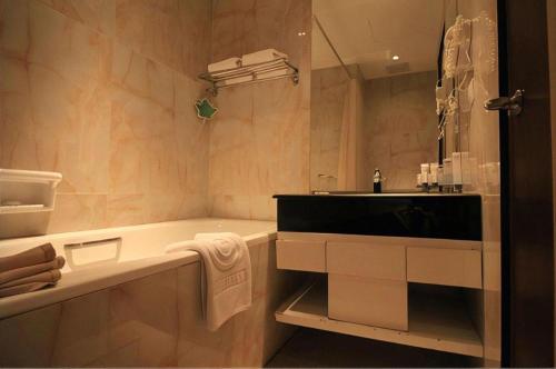 un baño con lavabo y bañera en G'Sign Hotel Banjarmasin, en Sungai Lutus
