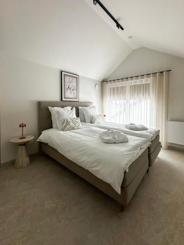 a bedroom with a large white bed with a window at Inspire Residence and private Wellness in Tongeren