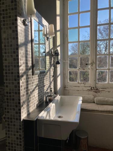 ein weißes Waschbecken im Bad mit Fenster in der Unterkunft La Manufacture Royale 1739 in Montolieu