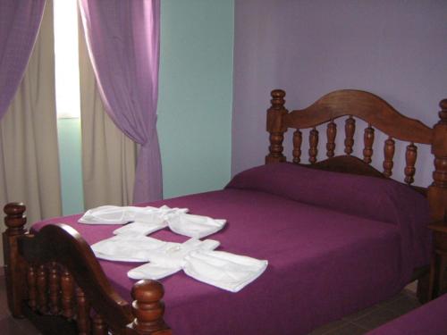 Una cama con sábanas moradas y toallas blancas. en Balcon de los Molles en Santa Rosa de Calamuchita