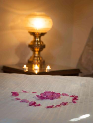 a pile of pink flowers on a bed with a lamp at Oinoessa Traditional Boutique Guest Houses in Lofou