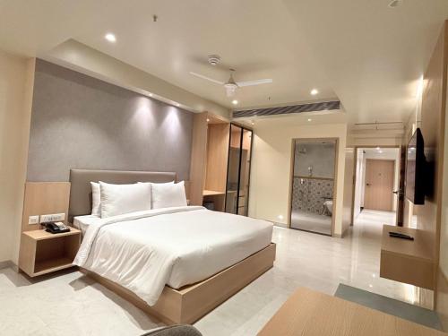 een slaapkamer met een groot wit bed en een televisie bij Samrat Studios in Pune