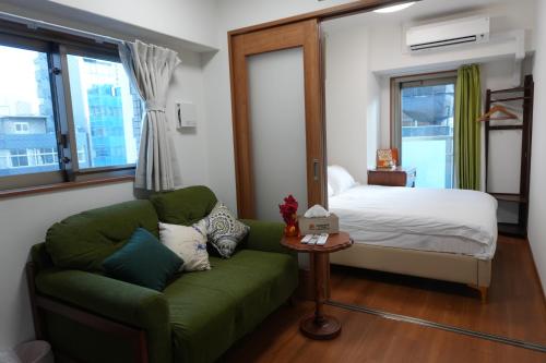 een slaapkamer met een groene bank en een bed bij Landmark Sunshine Hotel in Osaka