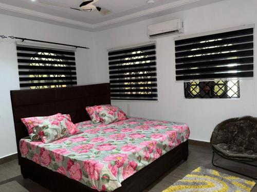 a bedroom with a bed with pink sheets and windows at Miky Hillside Lodge in Sunyani