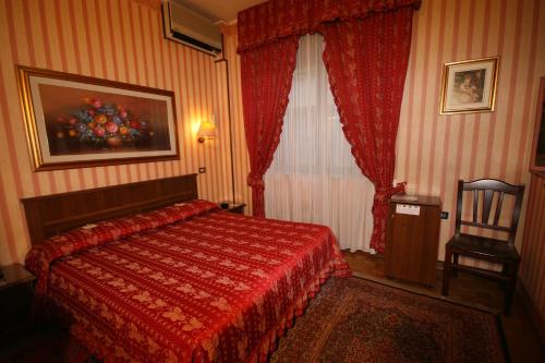 a bedroom with a red bed and a chair at Hotel Italia City Center in Mantova