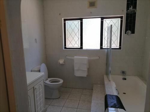 a bathroom with a toilet and a tub and a window at 850 Munro in Margate