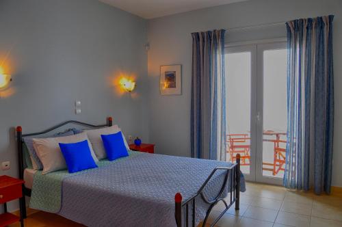 um quarto com uma cama com almofadas azuis e uma varanda em Pyrgos Zante Suites em Alikanas